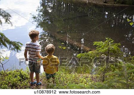 Stock Image - Brothers playing near lake. Fotosearch