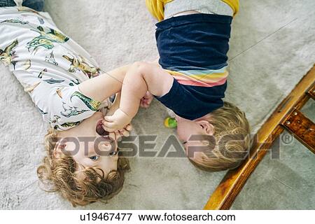 Stock Photo - Brothers playing on carpet at home. Fotosearch
