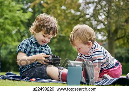 Brothers sharing food in park View Large Photo Image Stock Image - Brothers sharing food in park. Fotosearch