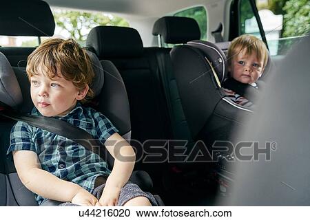 Brothers strapped onto child car seats in the back seat of a family car. View Large Photo Image Stock Image - Brothers strapped onto child car seats in the back seat of a family car.. Fotosearch