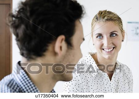 Picture - Businessman and businesswoman talking in office. Fotosearch