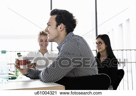 Stock Image - Businessman and businesswomen at meeting in office. Fotosearch