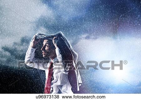 Stock Photo - Businessman Caught in heavy Rain hiding under his jacket. Fotosearch