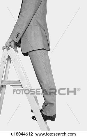 Stock Image - Businessman climbing ladder in black and white. Fotosearch