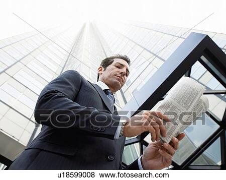 Stock Photo - Businessman reading the newspaper outside office building. Fotosearch