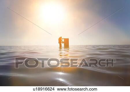 Picture - Businessman Standing in the Ocean Searching Through a Filing Cabinet. Fotosearch
