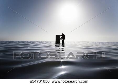 Businessman Standing in the Ocean Searching Through a Filing Cabinet View Large Photo Image Stock Photograph - Businessman Standing in the Ocean Searching Through a Filing Cabinet. Fotosearch