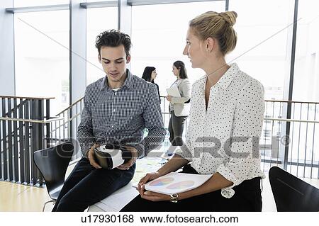 Businessman with VR headset and businesswoman talking in office, colleagues in background View Large Photo Image Stock Photo - Businessman with VR headset and businesswoman talking in office, colleagues in background. Fotosearch