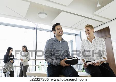 Businessman with VR headset and businesswoman talking in office, colleagues in background View Large Photo Image Stock Photography - Businessman with VR headset and businesswoman talking in office, colleagues in background. Fotosearch
