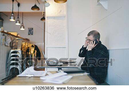 Businessman working on laptop and using smartphone in restaurant View Large Photo Image Stock Photograph - Businessman working on laptop and using smartphone in restaurant. Fotosearch