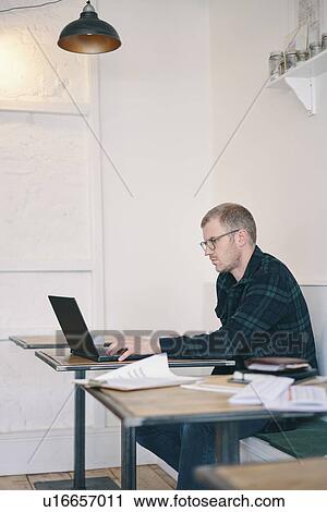Stock Image - Businessman working on laptop in restaurant. Fotosearch