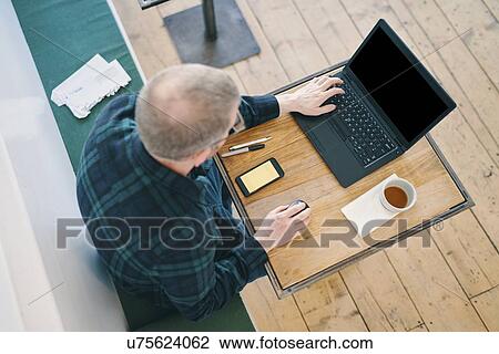 Businessman working on laptop in restaurant View Large Photo Image Stock Image - Businessman working on laptop in restaurant. Fotosearch
