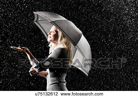 Stock Image - Businesswoman Standing Under Umbrella in rain. Fotosearch