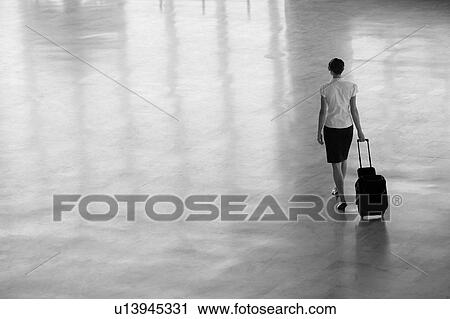 Stock Image - Businesswoman Walking With Wheeled Suitcase. Fotosearch