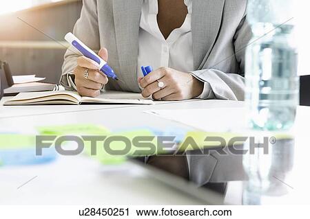 Businesswoman writing notes in office View Large Photo Image Stock Image - Businesswoman writing notes in office. Fotosearch