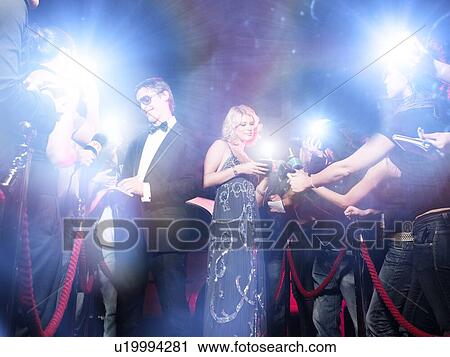 Stock Image - Celebrity couple arriving a premiere with paparazzi cameras and flashes. Fotosearch