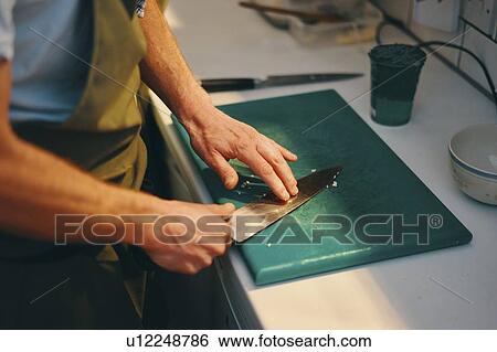 Chef holding knife on chopping board in kitchen View Large Photo Image Stock Photograph - Chef holding knife on chopping board in kitchen. Fotosearch