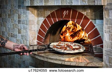 Chef placing pizza into stone oven View Large Photo Image Stock Photography - Chef placing pizza into stone oven. Fotosearch