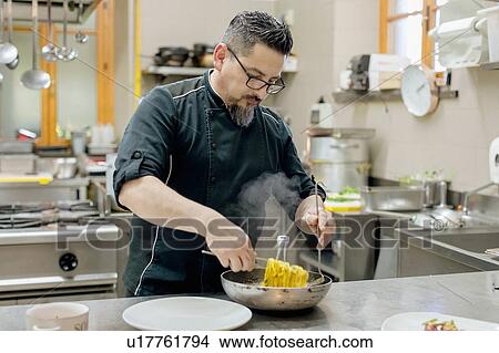 Picture - Chef preparing pasta in kitchen. Fotosearch