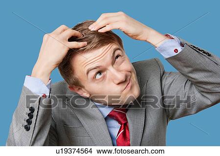 Picture - Close-up of confused businessman touching head with funny face. Fotosearch