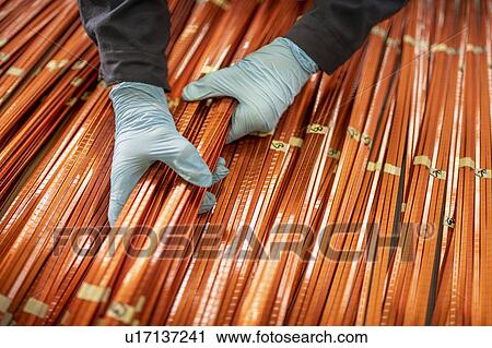 Stock Image - Close up of electrical engineer inspecting copper windings in electrical engineering factory. Fotosearch
