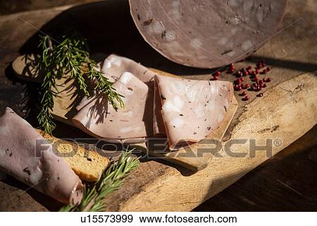 Stock Photo - Close up of salami slices, rosemary, peppercorn. Fotosearch