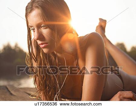 Close-up of woman lying on jetty listening to mp3 player View Large Photo Image Stock Photograph - Close-up of woman lying on jetty listening to mp3 player. Fotosearch