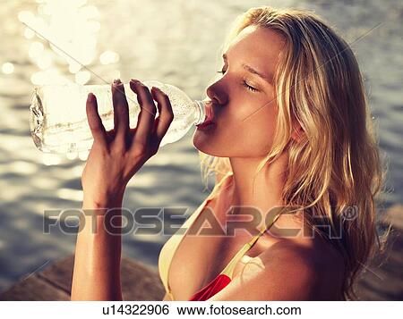 Close-up of young woman in bikini drinking from bottle on jetty View Large Photo Image Stock Photograph - Close-up of young woman in bikini drinking from bottle on jetty. Fotosearch
