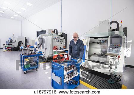 Stock Photograph - CNC lathes and operator in medical scientific factory. Fotosearch