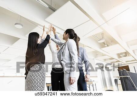 Stock Image - Colleagues sharing a high five moment in office. Fotosearch