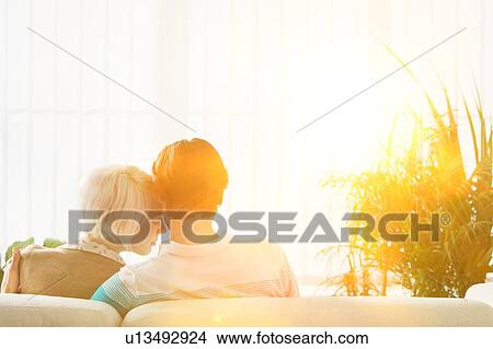 Couple embracing sitting on sofa rear view View Large Photo Image Picture - Couple embracing sitting on sofa rear view. Fotosearch