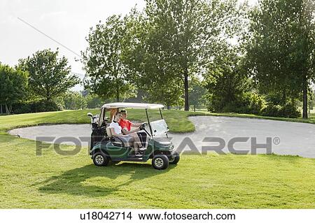 Picture - Couple riding on buggy on golf course. Fotosearch
