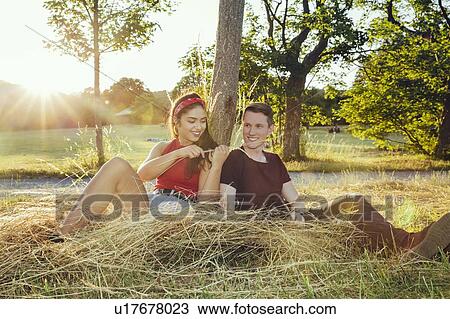 Stock Image - Couple sitting on loose hay, Wilhelminenberg, Vienna, Austria. Fotosearch
