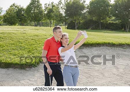 Picture - Couple taking selfie on golf course. Fotosearch