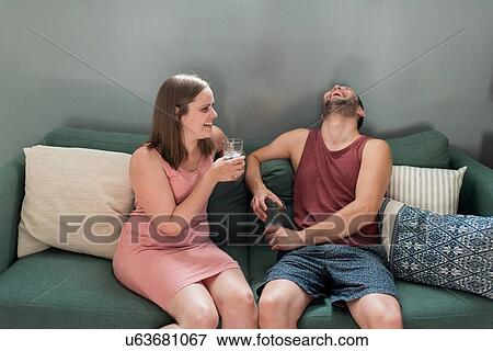 Couple talking and laughing on sofa at home View Large Photo Image Stock Photo - Couple talking and laughing on sofa at home. Fotosearch