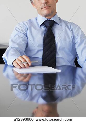 Stock Image - Cropped photo of businessman sitting at table in office. Fotosearch