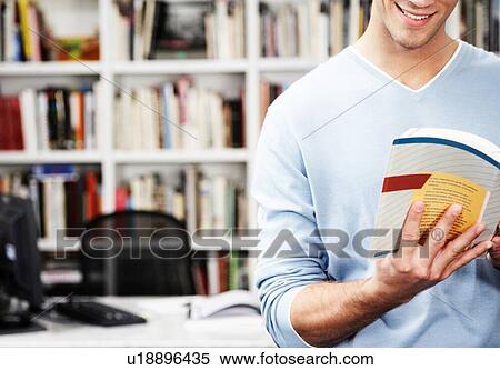 Stock Photography - Cropped photo of student reading textbook from home office. Fotosearch
