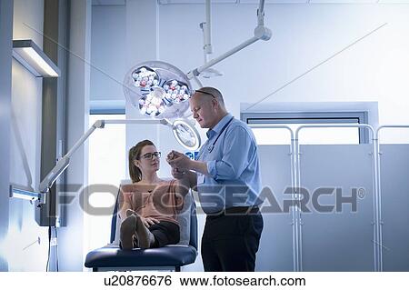 Doctor inspecting patient's hand in intensive care unit in hospital setting View Large Photo Image Stock Photograph - Doctor inspecting patient's hand in intensive care unit in hospital setting. Fotosearch