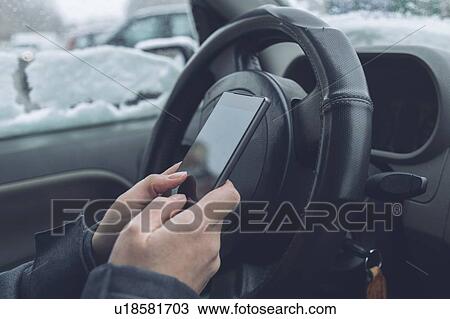 Stock Image - Driver texting in a parked car. Fotosearch