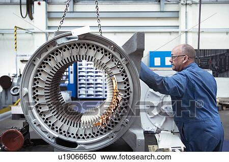Stock Image - Electrical engineer craning generator stator in electrical engineering factory. Fotosearch