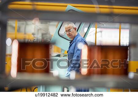 Stock Image - Electrical engineer operating copper wire winding machine in electrical engineering factory. Fotosearch
