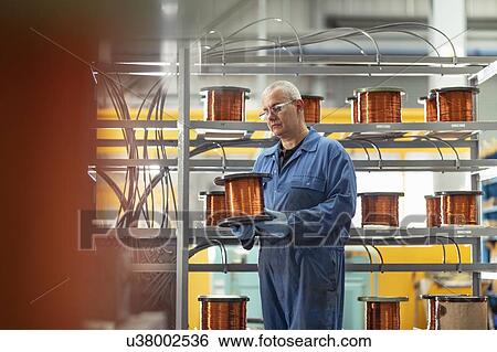 Stock Photograph - Electrical engineer with reel of copper wire in electrical engineering factory. Fotosearch