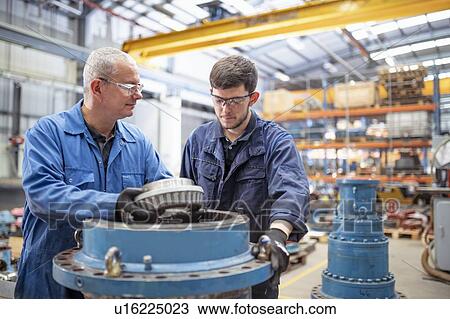 Engineer and apprentice installing bearings into pump house in electrical engineering factory View Large Photo Image Stock Image - Engineer and apprentice installing bearings into pump house in electrical engineering factory. Fotosearch