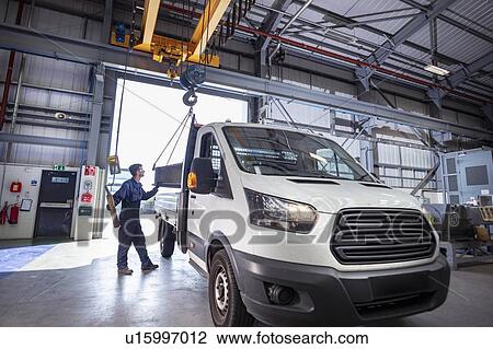 Stock Image - Engineer loading parts into truck in electrical engineering factory. Fotosearch