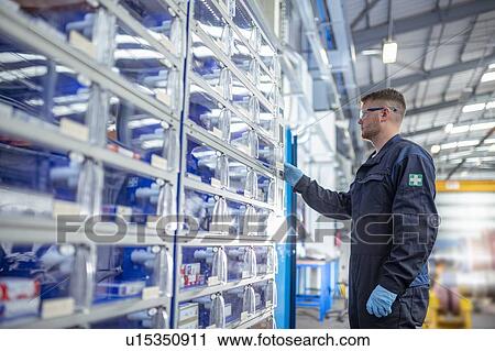 Stock Image - Engineer operating tool and parts vending machine in electrical engineering factory. Fotosearch