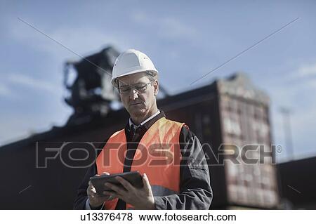 Engineer using digital tablet at port View Large Photo Image Stock Photo - Engineer using digital tablet at port. Fotosearch