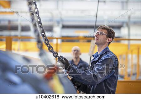 Stock Photo - Engineers craning generator in electrical engineering factory. Fotosearch