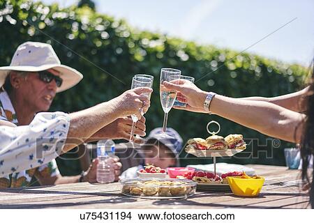 Picture - Family celebrating with champagne and cakes in garden. Fotosearch