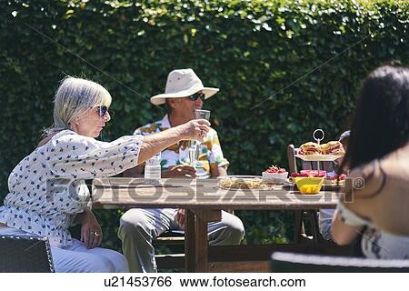Stock Photograph - Family celebrating with champagne and cakes in garden. Fotosearch