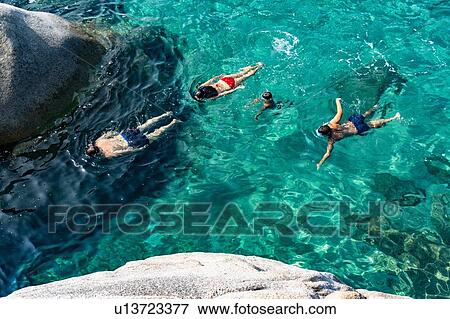 Stock Photo - Family of four swimming in crystal clear sea, Cagliari, Sardinia. Fotosearch